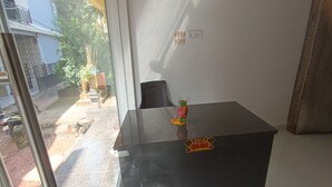 Een kamer met een zwarte tafel, een stoel, een raam en uitzicht op het buiten.