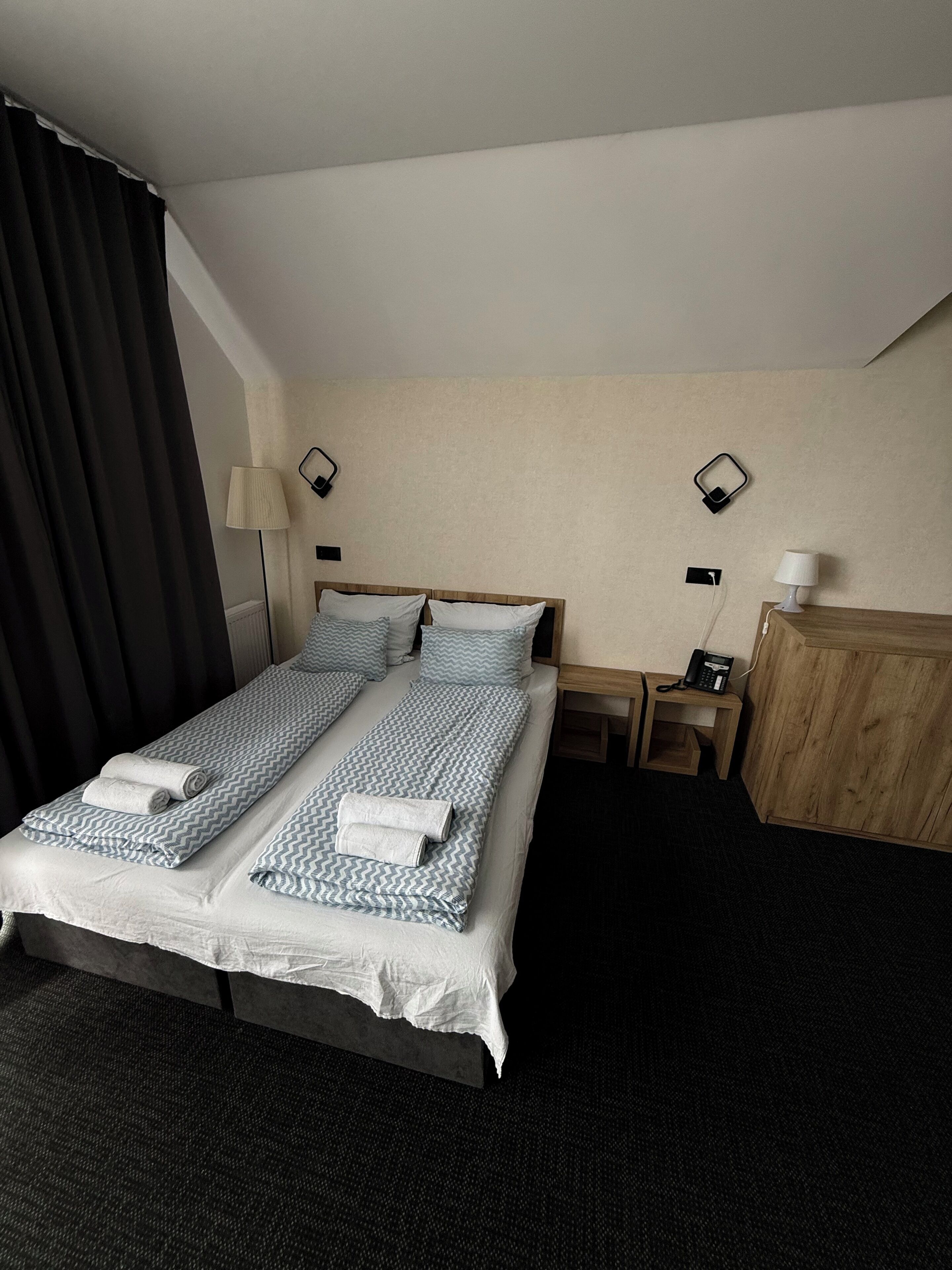 Une chambre d’hôtel comprenant un lit, deux tables de chevet, une lampe, un téléphone et un placard.