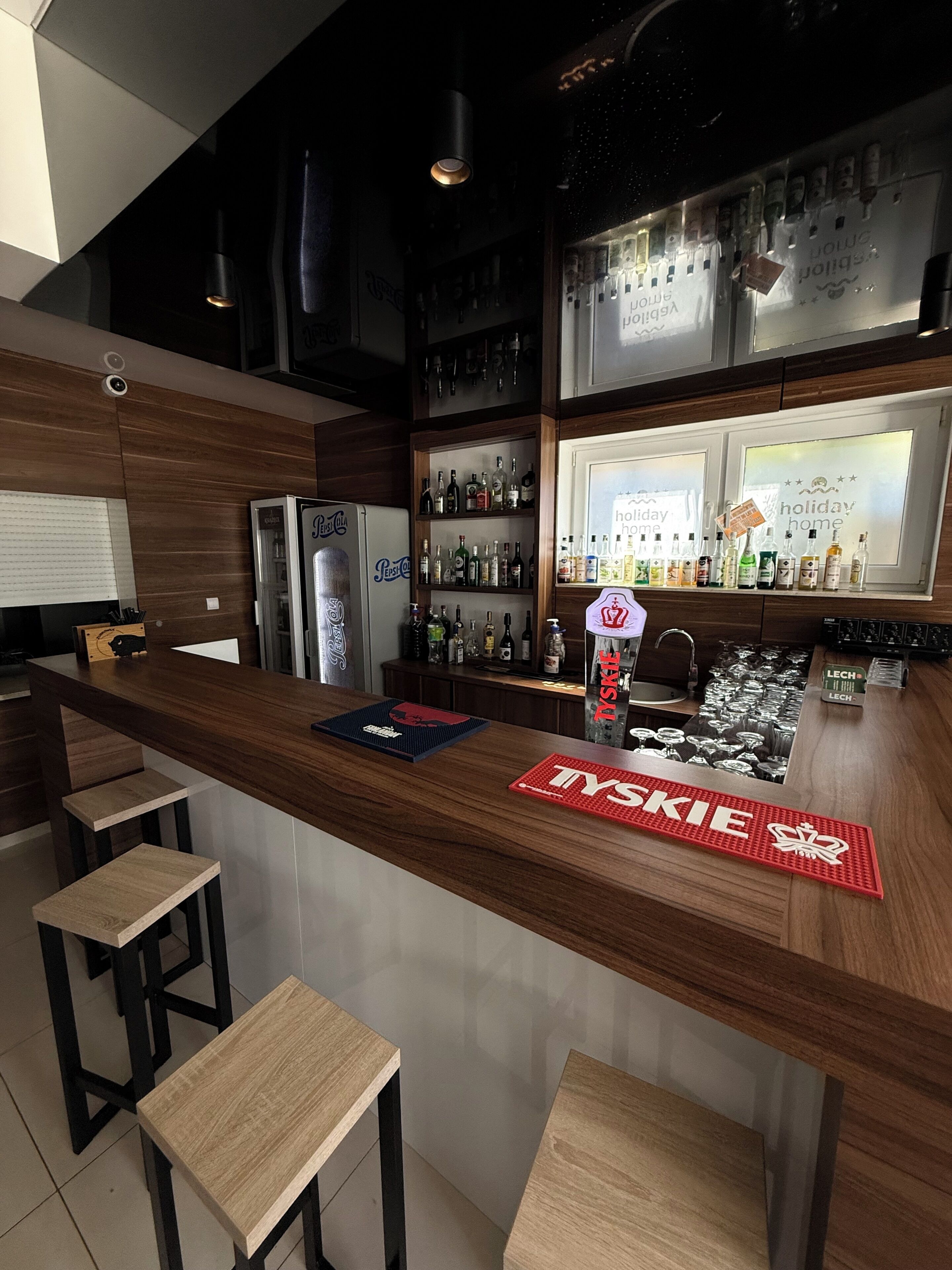Eine moderne Bar mit einer Holztheke, Barhocker und einer Auswahl an Spirituosen.