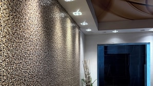 Un interior moderno con pared texturizada, luces empotradas en el techo y un banco de madera.