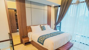 Une chambre d’hôtel moderne avec un grand lit, une armoire intégrée et une vue dégagée à travers des rideaux légers.