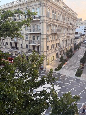 Un edifici de diverses plantes amb balcons, un carrer al davant i arbres al primer pla.