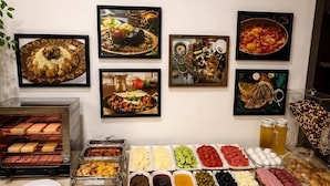 A buffet with various food items and a wall with framed pictures. - La Casa Boutique Nizami (Baku)