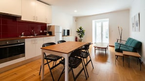 Eine moderne Küche mit weißen Schränken, einer roten Spritzschutzwand und einem Essbereich mit einem Holztisch und schwarzen Stühlen.