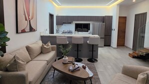 Uma sala de estar moderna com sofá, mesa de centro e vista para a cozinha.