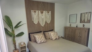 A bedroom with a bed, a plant, a wooden headboard, a cabinet, and a mirror. - 2 minutes from the beach: Charming apartment with outdoor space and secure parking (Antibes)