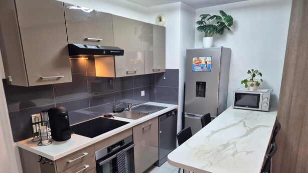 A modern kitchen with stainless steel appliances, a marble countertop, and a bar stool. - 2 minutes from the beach: Charming apartment with outdoor space and secure parking (Antibes)