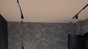 Un dormitorio moderno con un cabecero de madera, una mesita de noche con lámpara y una puerta oscura.