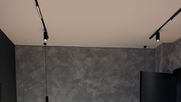 Un dormitorio moderno con un cabecero de madera, una mesita de noche con lámpara y una puerta oscura.