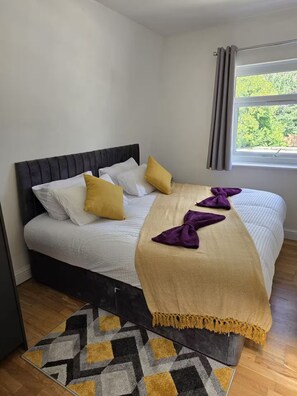 Ein Bett mit Kopfteil, Kissen, Decke und Teppich.