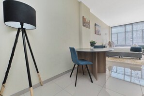 A modern living room with a round dining table, a blue chair, a floor lamp, and a sofa. - Urban Luxe Studio Illovo Mews by ctha (Sandton)