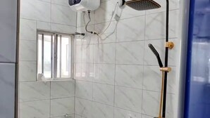 Un baño con inodoro, ducha con cabezal de ducha manual y aire acondicionado de pared.