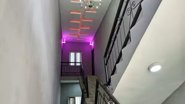Una escalera con barandilla de metal, un candelabro y un techo con iluminación empotrada.