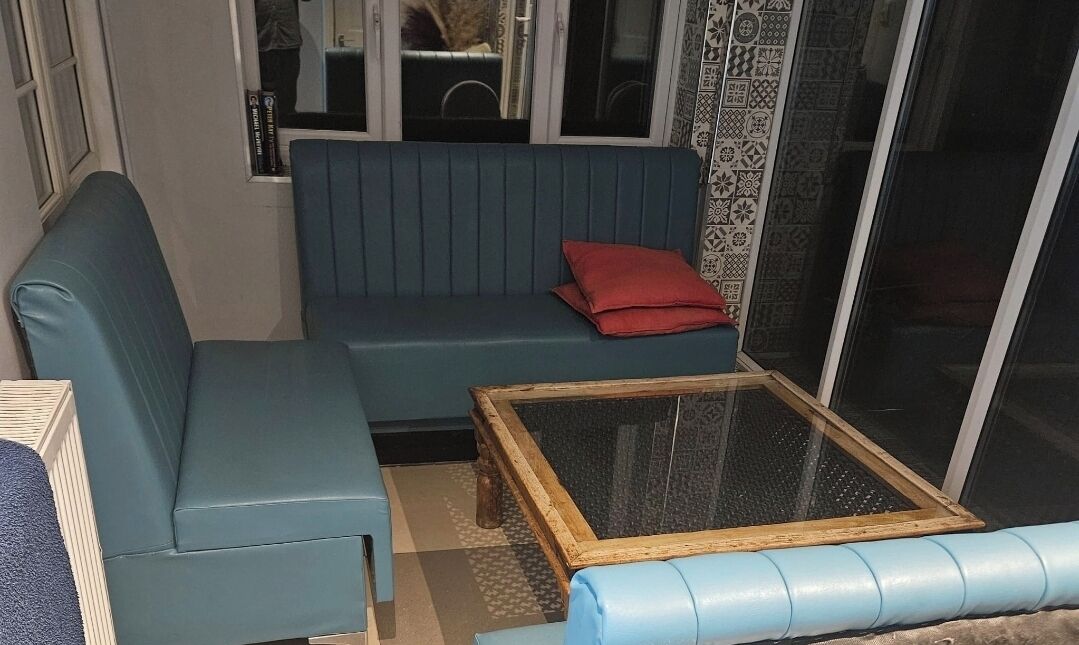 Una habitación con un sofá azul, un cojín rojo y una mesa de centro de cristal.