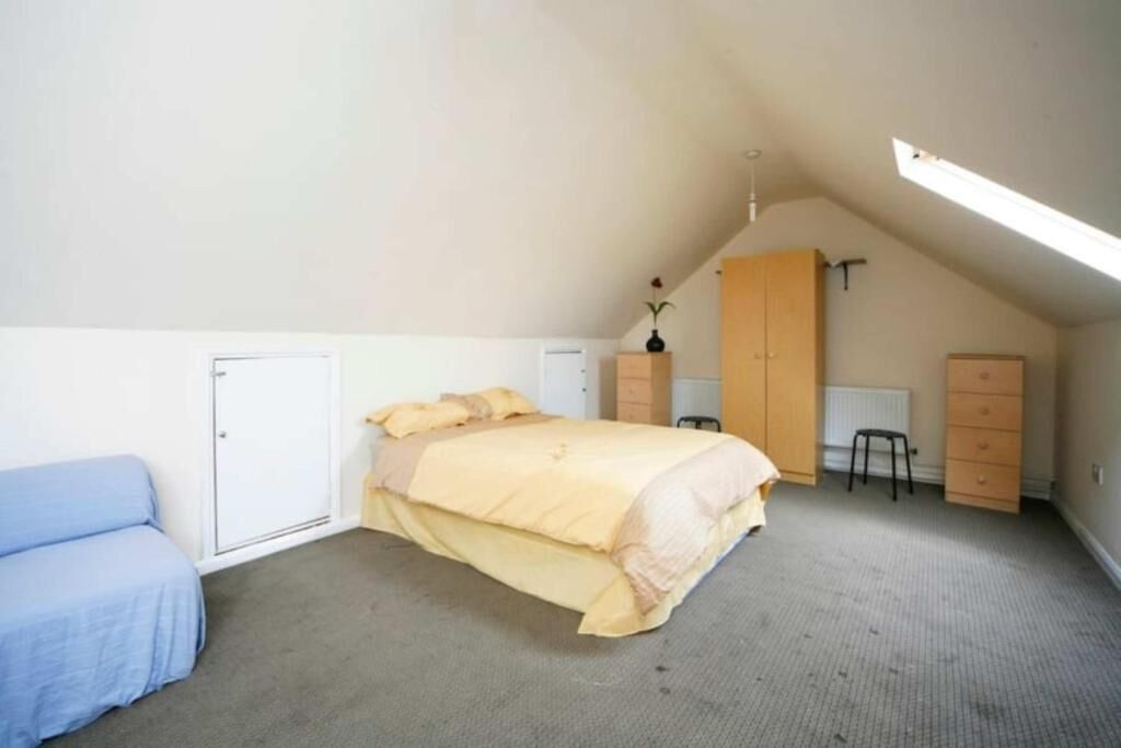 A bedroom with a bed, a chair, a wardrobe, and a desk.