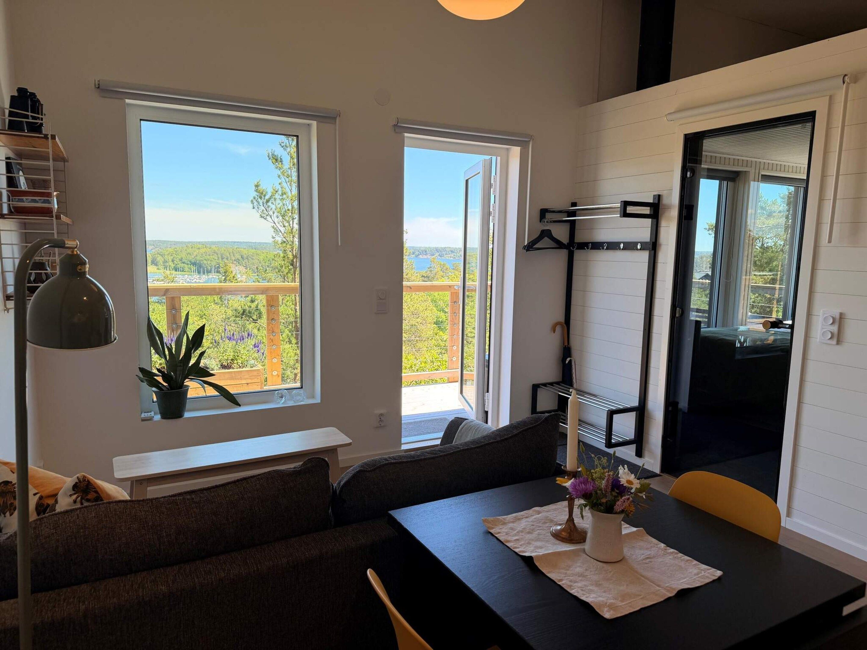A room with a sofa, dining table, and a view of a balcony with a railing.