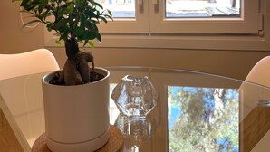 A room with a glass table, a potted plant, and a view through a window with a door. - Casa Verde | Minimal & Cozy Stay (Elliniko)