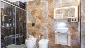 Un baño moderno con ducha envuelta en vidrio, un bidé, un lavabo y un espejo.