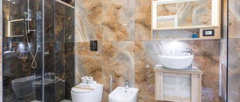 A modern bathroom with a glass-enclosed shower, a bidet, a sink, and a mirror.