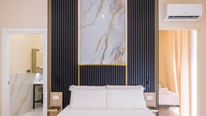 Habitación de hotel con cama, un espejo grande, aire acondicionado de pared y un baño visible a través de una puerta abierta.