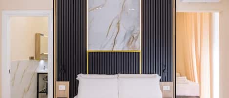 Quarto de hotel com cama, um espelho grande, ar condicionado fixado na parede e banheiro visível através de uma porta aberta.