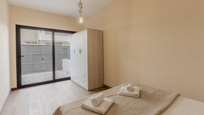 A bedroom with a bed, a wardrobe, a sliding glass door to a balcony, and a hanging light fixture. - #394 Albufeira Escape | 3-Bedroom Villa with Shared Pool (Albufeira)