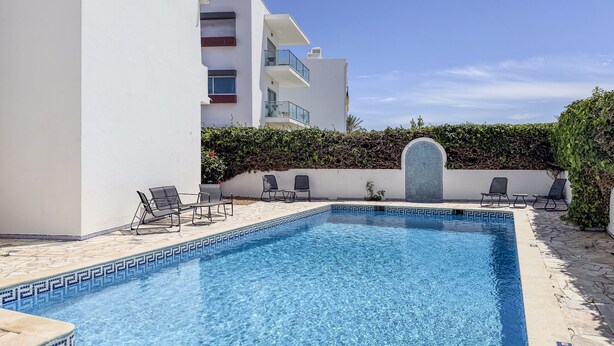 A swimming pool with a geometric tile pattern, surrounded by lounge chairs and a hedge. - #394 Albufeira Escape | 3-Bedroom Villa with Shared Pool (Albufeira)