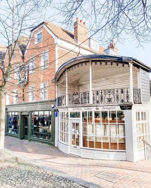 Ein traditionelles Gebäude mit einem Laden im Erdgeschoss, ausgestattet mit großen Fenstern und einer geschwungenen Fassade.