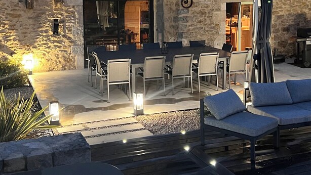 Un edificio in pietra con area salotto esterna, piscina e patio.