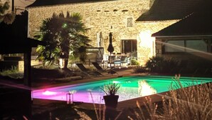 Un edificio in pietra con piscina, area salotto all'aperto e patio.