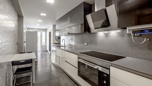 Una cucina moderna con forno a incasso, lavastoviglie e cappa aspirante in acciaio inox.