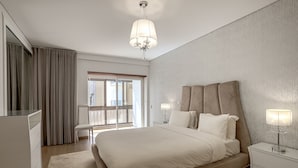 Una moderna camera d'albergo con un ampio letto, una scrivania, una sedia e un balcone.