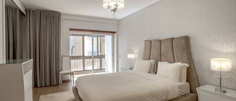 Una habitación de hotel moderna con una cama grande, un escritorio, una silla y un balcón.