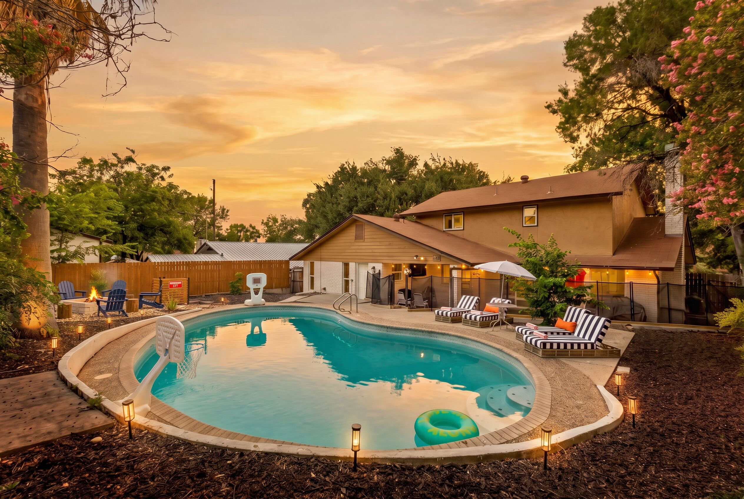 Ein Garten mit Swimmingpool, Liegestühlen und Grillplatz.