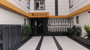 Ein Gebäude mit einem Schild, auf dem 'ÖKMEN RESIDENCE NO:3' steht, und einem gefliesten Eingangsbereich.