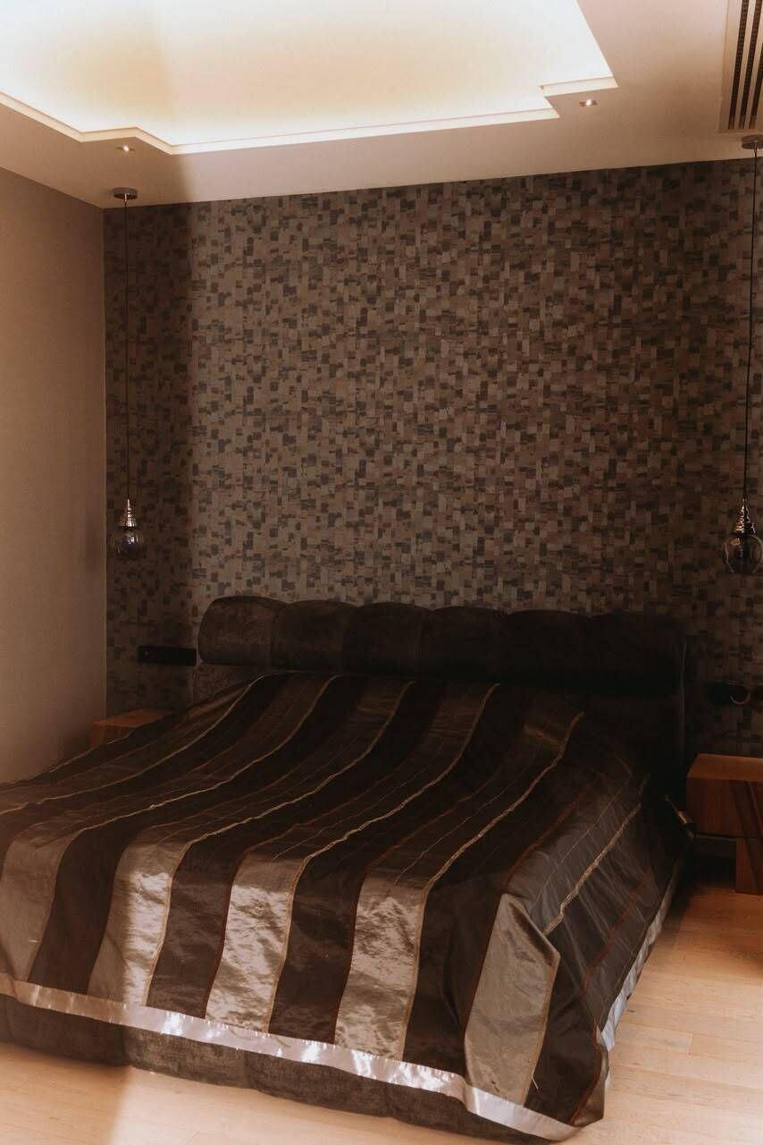 A bedroom with a large bed, a patterned wall, and a skylight.