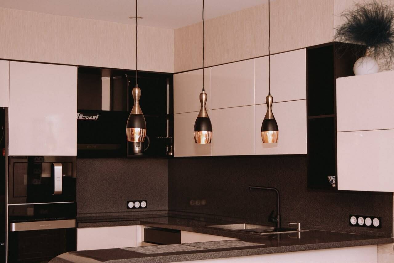 Cozinha moderna com luminárias pendentes, forno embutido e pia.
