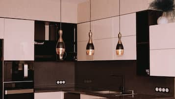 Cozinha moderna com luminárias pendentes, forno embutido e pia.