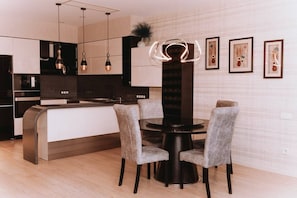 Una cocina moderna con una isla central, iluminación colgante y cuadros en la pared.