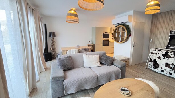 Een moderne woonkamer met een bank, een ronde salontafel en een tv-meubel.