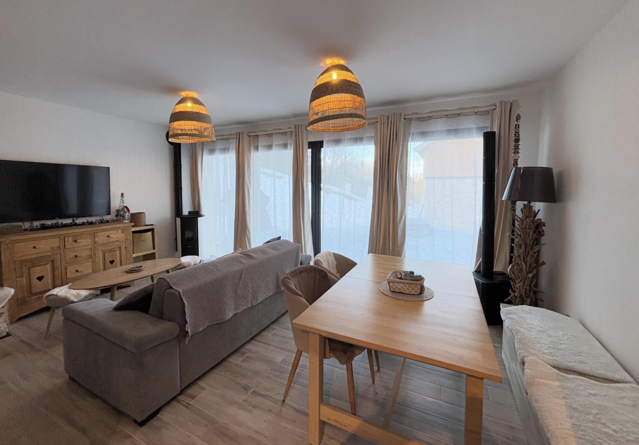 Ein modernes Wohnzimmer mit einer Couch, einem Esstisch und einem Fernseher.