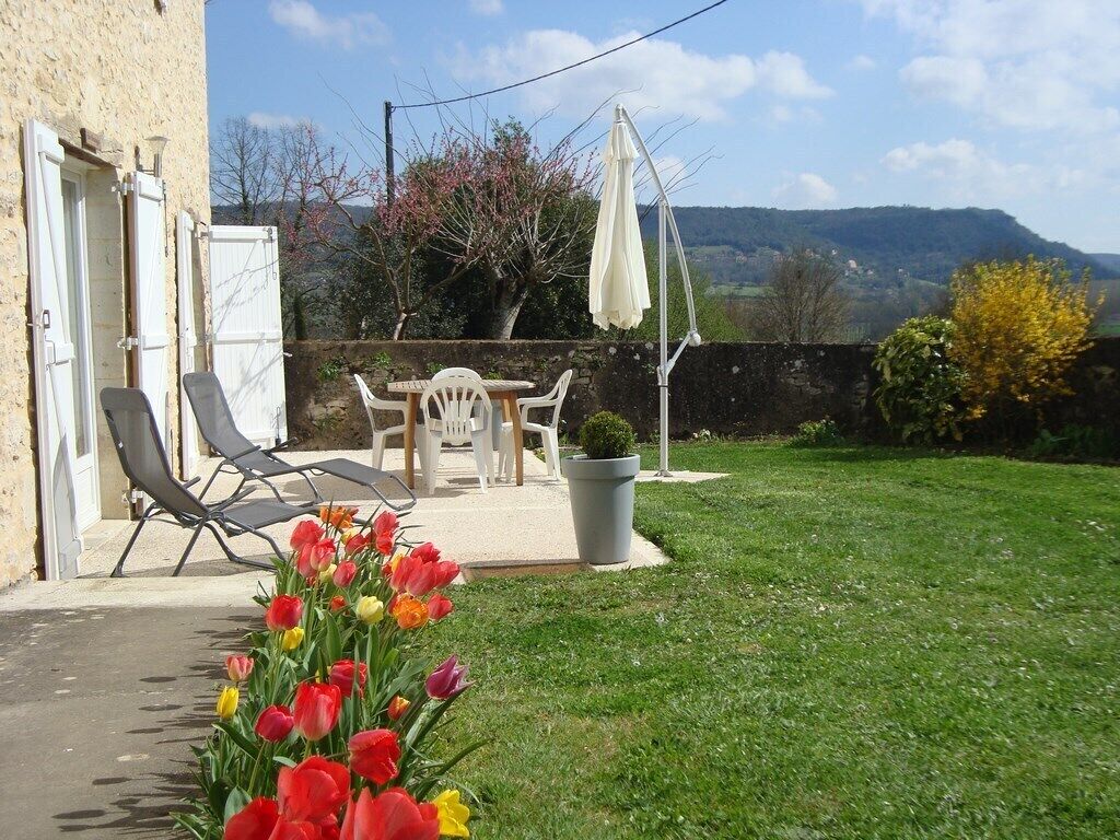 A patio with outdoor furniture, a potted plant, and a view of the countryside.