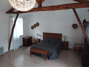 A bedroom with a wooden ceiling, a bed, bedside tables, a bench, and a hanging light fixture. - La Grange Vacation Rental in the Périgord Noir (Allas-les-Mines)