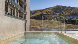 Una piscina con vistas a un edificio y un paisaje montañoso.