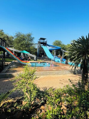 A water park with slides and a pool area surrounded by greenery.