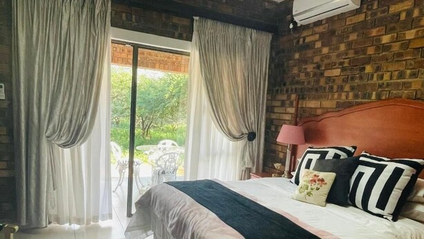 Un dormitorio con cama, cortinas, una lámpara y vistas al exterior.
