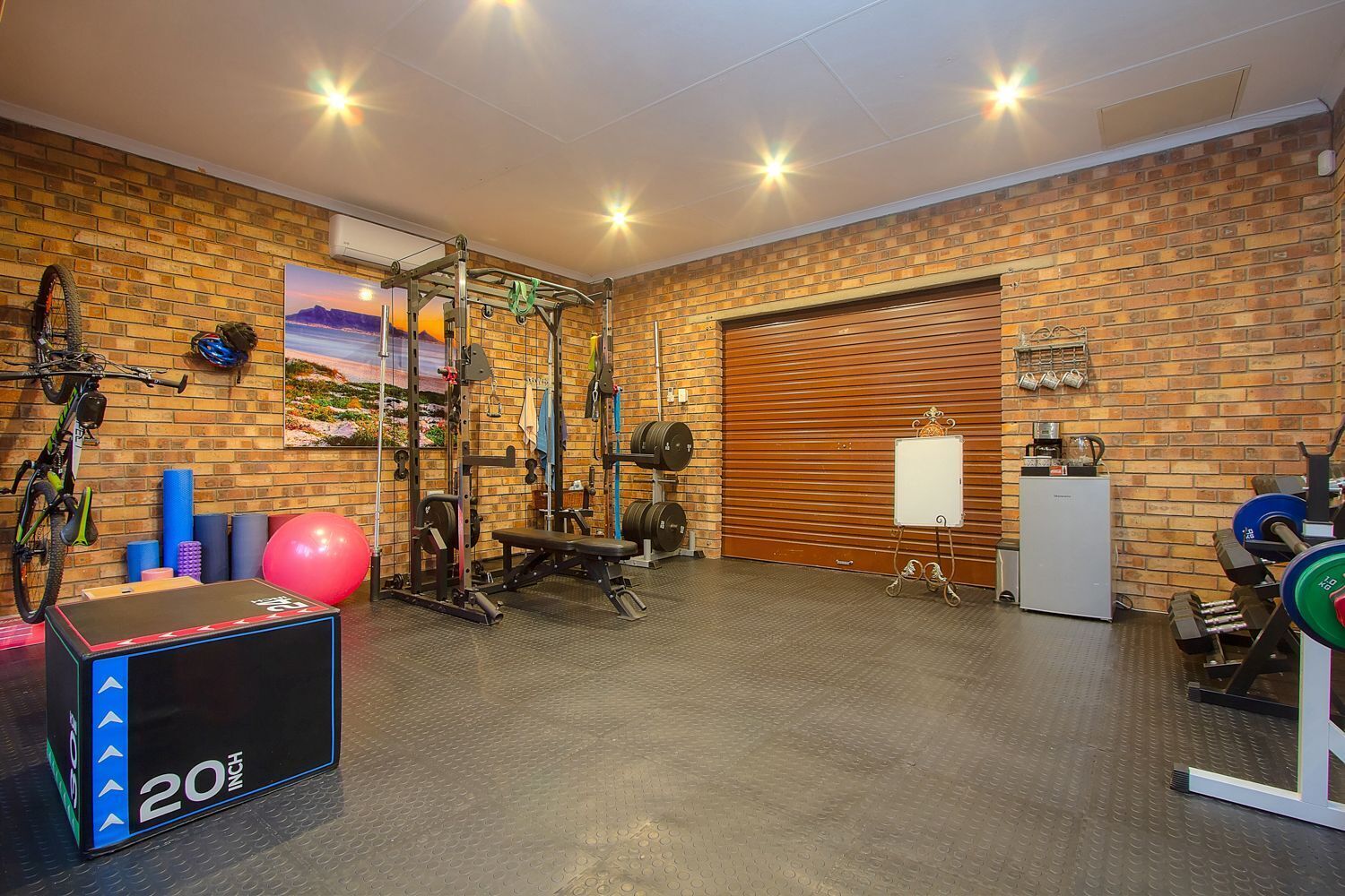 A gym with a brick wall, exercise equipment, a whiteboard, and a large window.