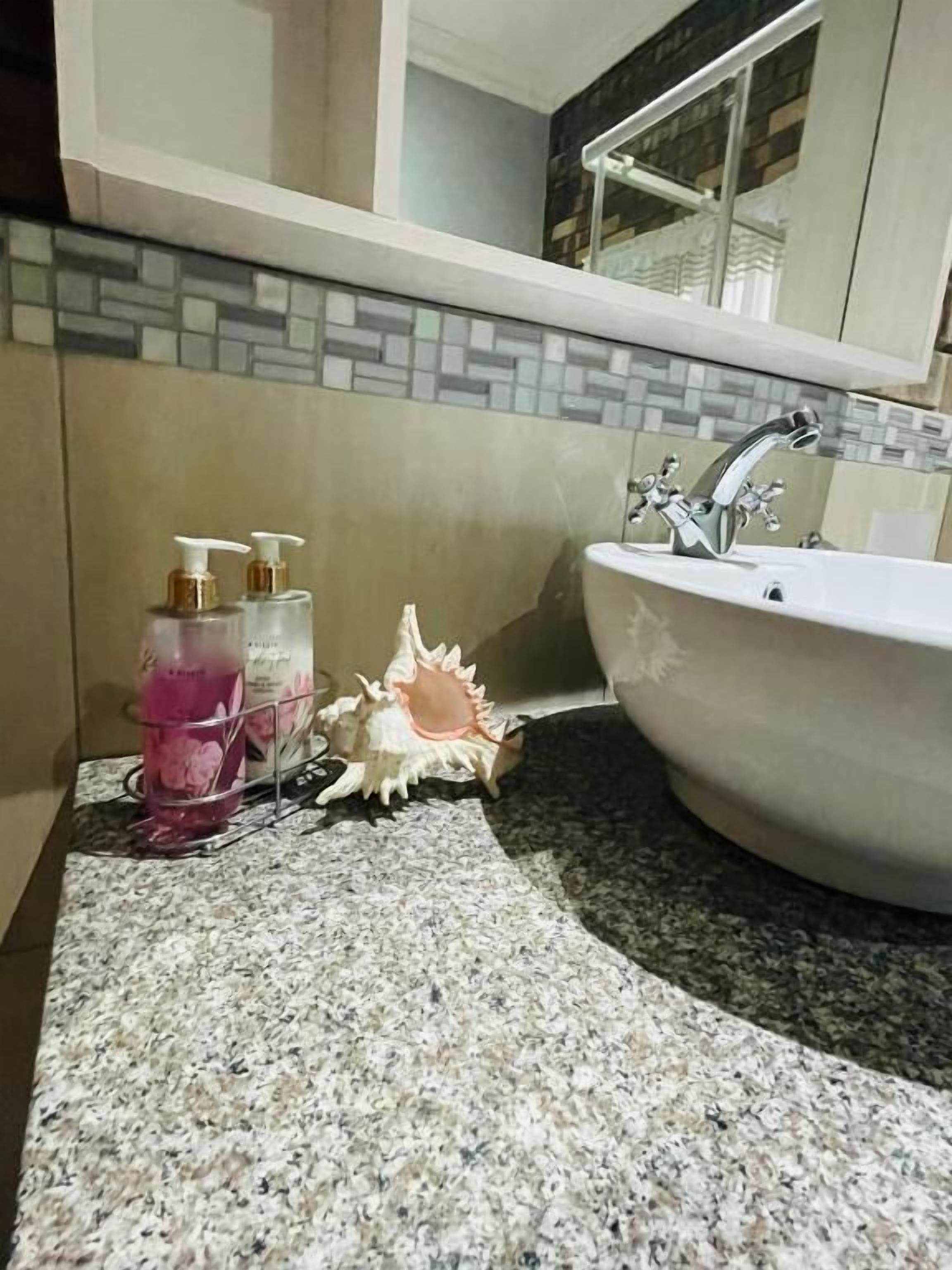 A bathroom with a granite countertop, a white sink, and a decorative shell.