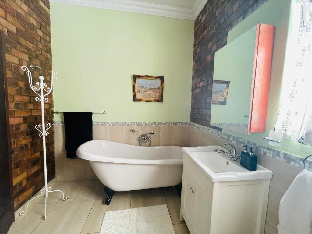 A bathroom with a bathtub, sink, and a mirror.