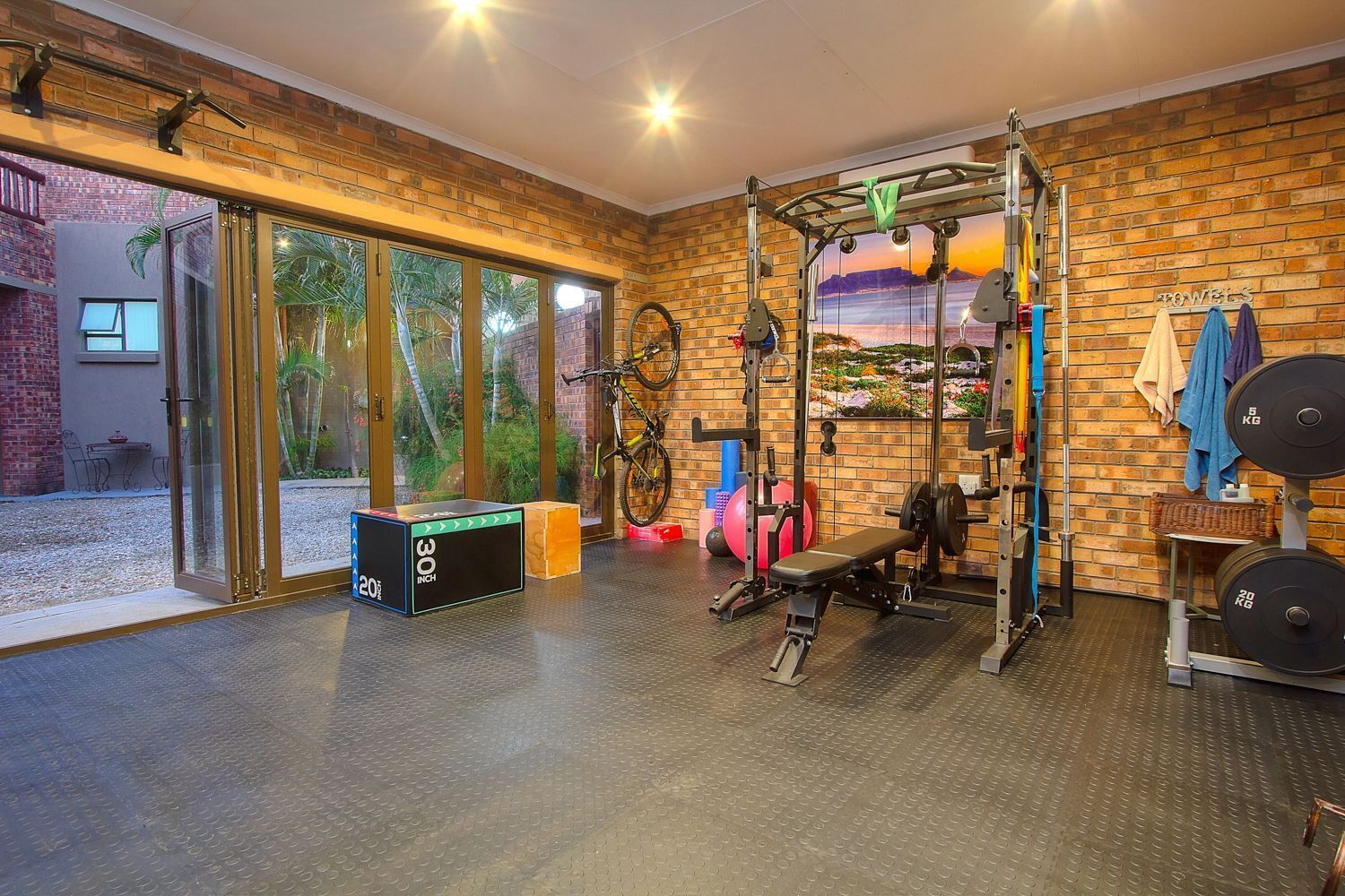 A gym with a brick wall, a window with a view, and a bench.